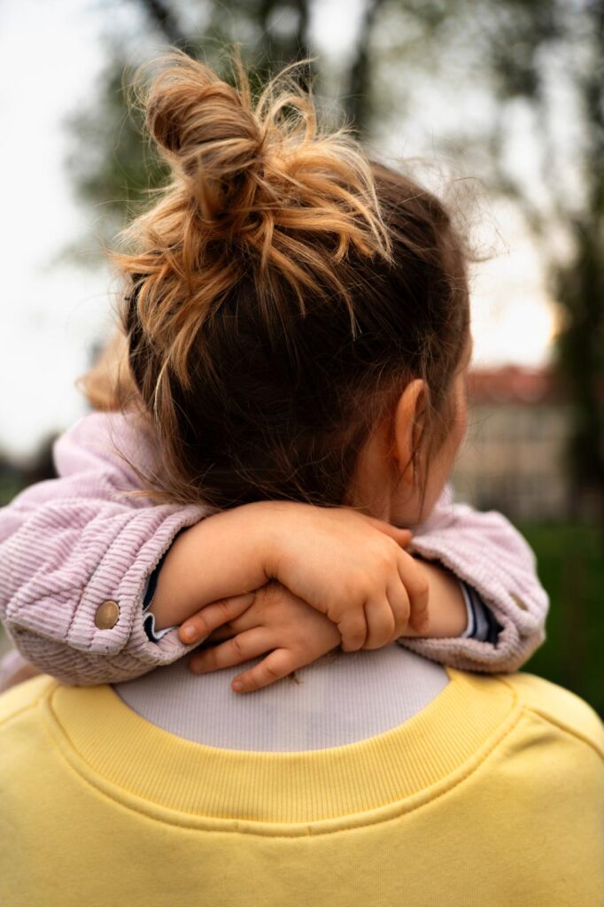 assistante maternelle de dos qui porte un enfant